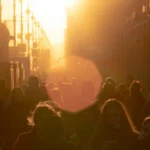 people walking in a city with sun in the background